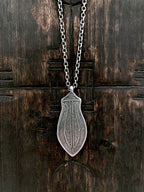 A sterling silver pendant with etched blade design, mounted on a silver chain