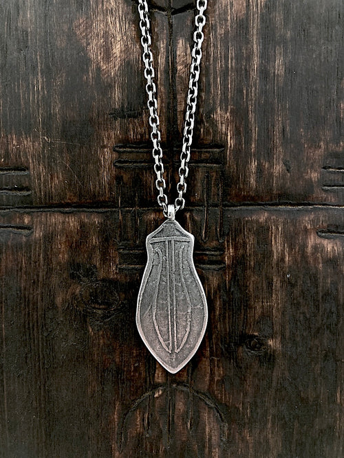A sterling silver pendant with etched blade design, mounted on a silver chain