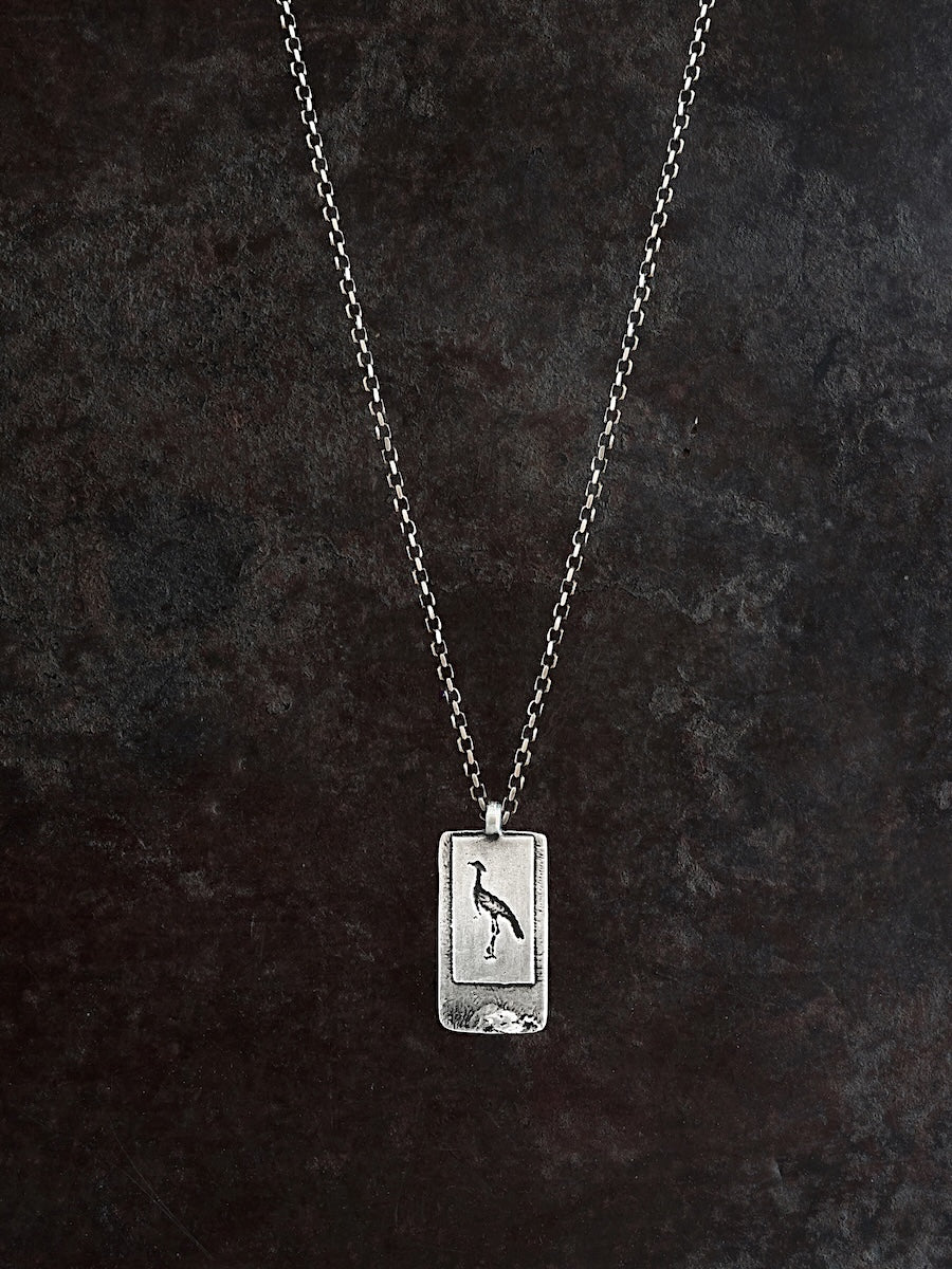 Silver necklace with a crane etched onto a rectangular pendant 