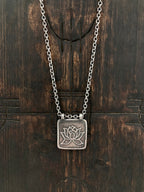An aged 925 sterling silver Lotus Flower necklace. The lotus represents beauty and purity. Our Lotus pendant has an organic border and wood block effect.