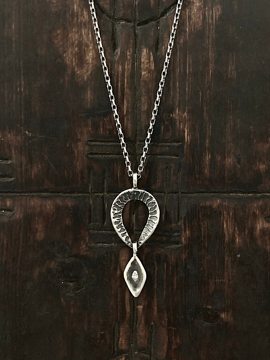 A silver necklace with a double drop pendant featuring an etched coral rock texture and a marquise diamond on the bottom pendant.