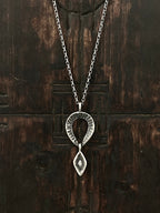 A silver necklace with a double drop pendant featuring an etched coral rock texture and a marquise diamond on the bottom pendant.