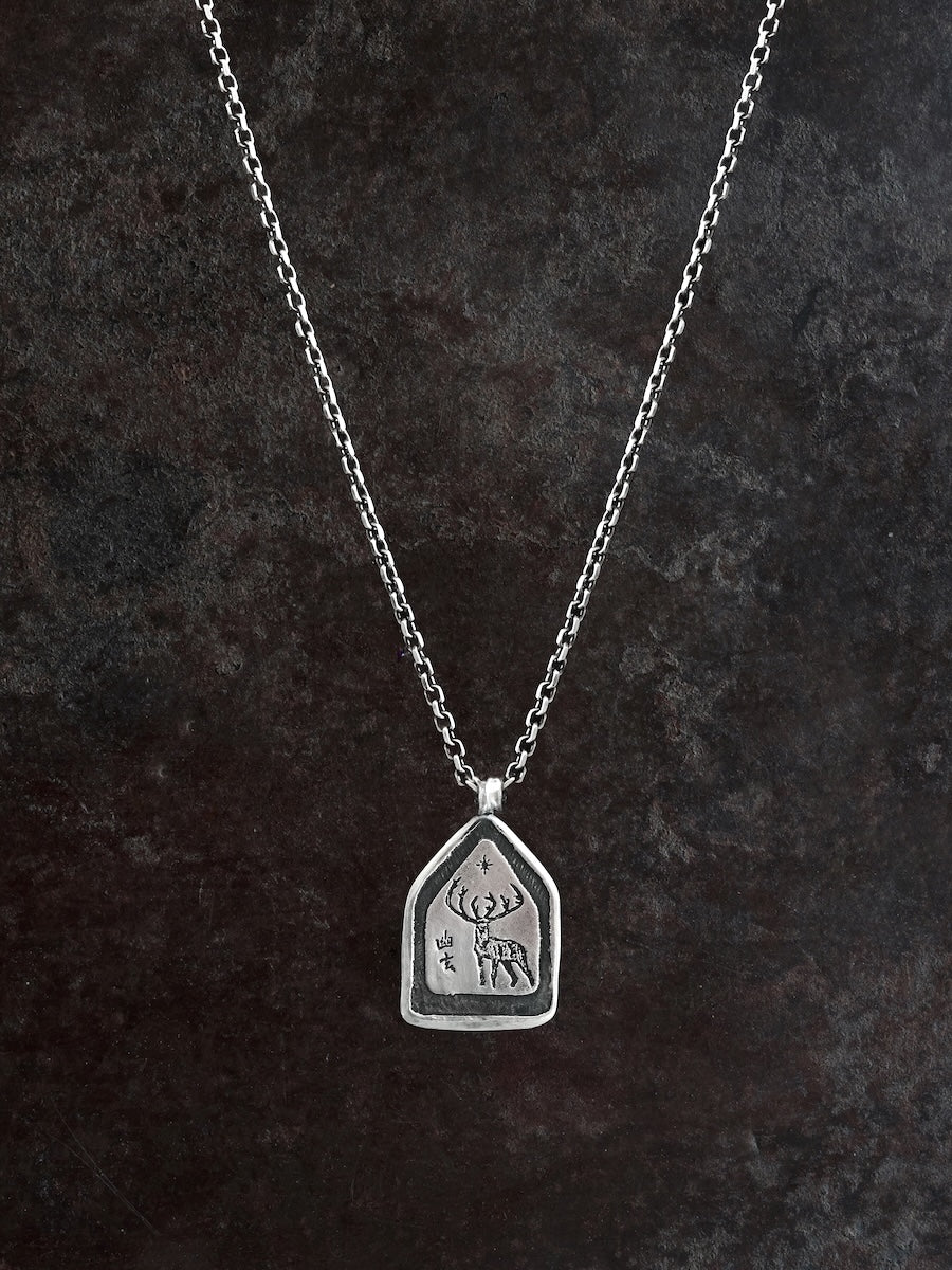 A etched deer on a sterling silver pendant