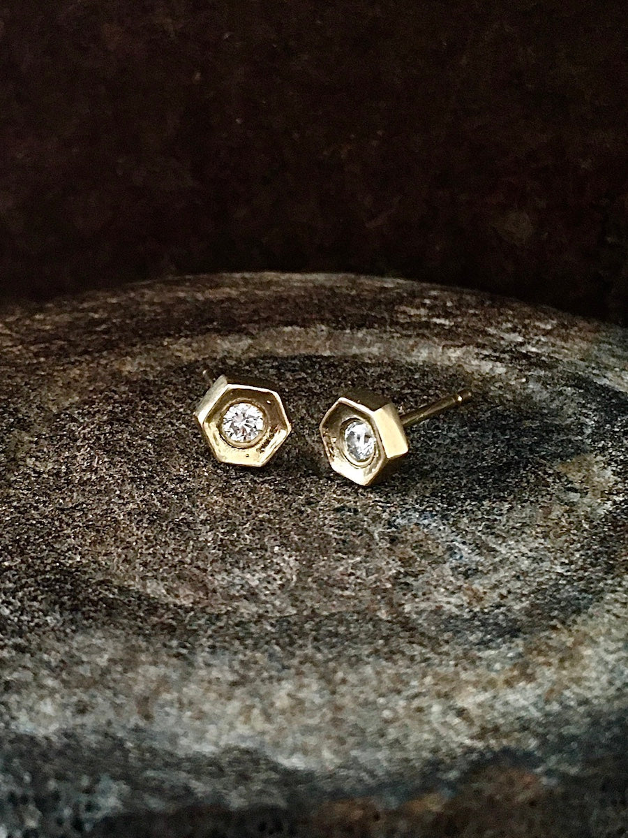 A pair of hexagon-shaped diamond stud earrings set in yellow gold.