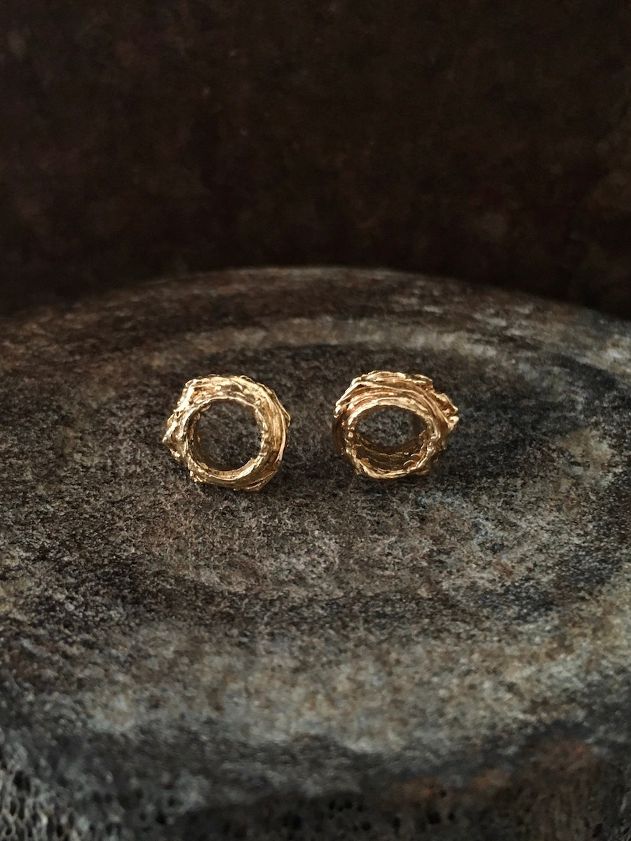 A pair of handmade 14k gold circle stud earrings inspired by spiritual vortex